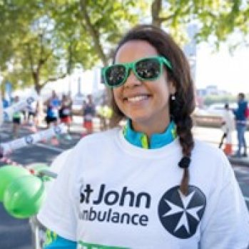 St John Volunteer at a running event, outside and smiling in branded t-shirt.